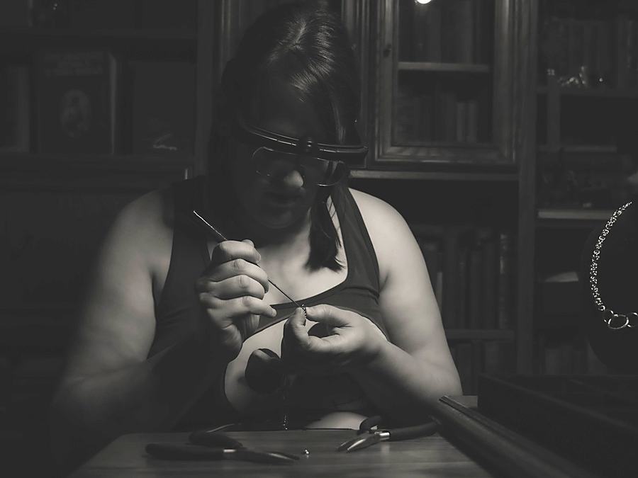 Melissa at the bench in magnifying loupes, closing a ring with pliers
